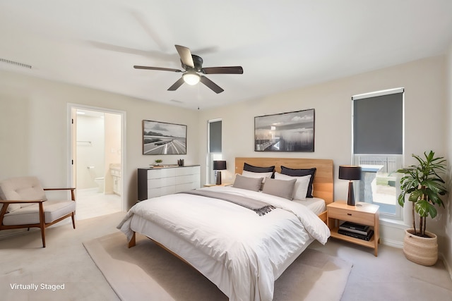 bedroom with ensuite bath, visible vents, a ceiling fan, and light colored carpet