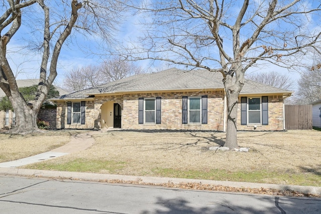 ranch-style home with brick siding, a shingled roof, and fence