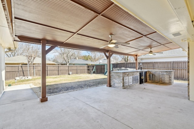 view of patio featuring a fenced backyard, visible vents, an outdoor kitchen, and a ceiling fan