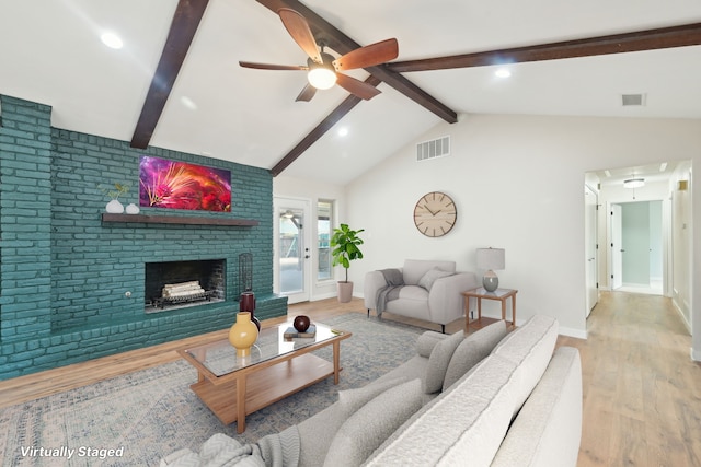 living area with vaulted ceiling with beams, wood finished floors, visible vents, baseboards, and a brick fireplace