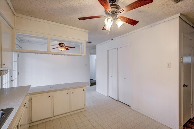 kitchen with light floors, light countertops, a ceiling fan, a sink, and a textured ceiling