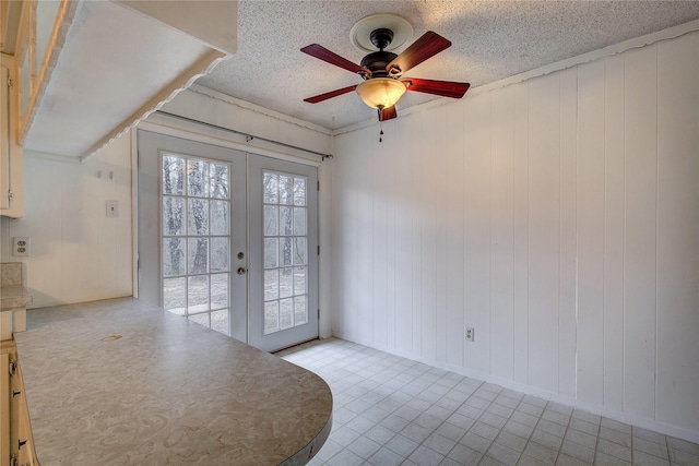 interior space featuring a ceiling fan, french doors, and a textured ceiling