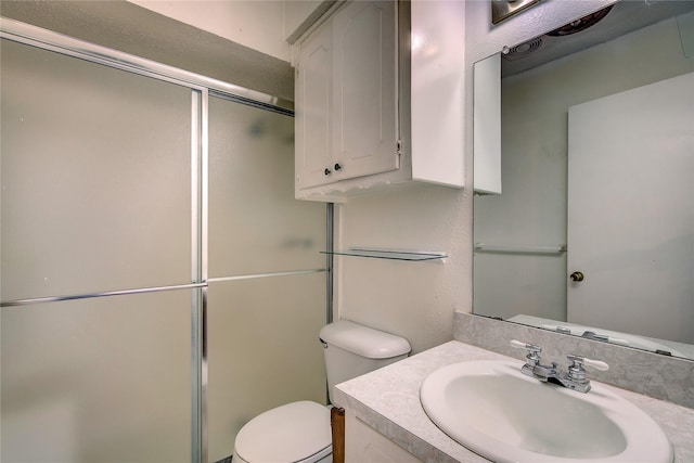 bathroom featuring a shower stall, toilet, and vanity