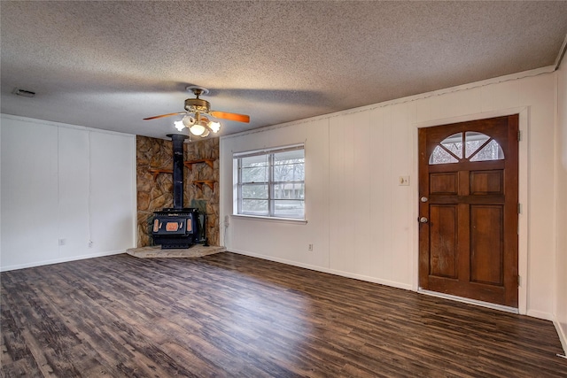 unfurnished living room with dark wood-style floors, a wood stove, a textured ceiling, and visible vents