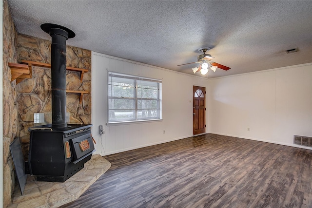 unfurnished living room featuring a wood stove, visible vents, and wood finished floors