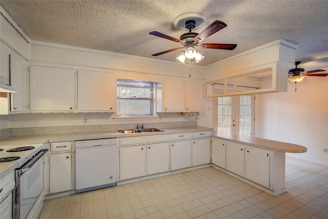 kitchen featuring light countertops, white cabinetry, a sink, white appliances, and a peninsula