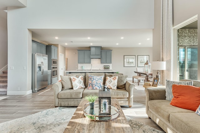 living room featuring recessed lighting, wood finish floors, stairway, and baseboards