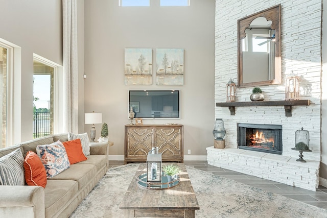 living room with a fireplace, a towering ceiling, baseboards, and wood finished floors