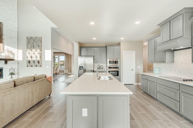 kitchen with appliances with stainless steel finishes, open floor plan, wood tiled floor, gray cabinetry, and a sink