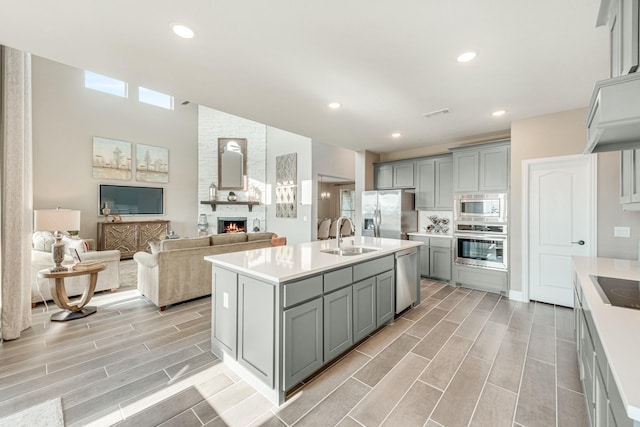 kitchen featuring stainless steel appliances, a sink, light countertops, and gray cabinetry