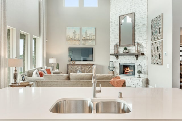 kitchen with a high ceiling, a fireplace, open floor plan, and a sink