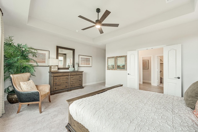 bedroom featuring a ceiling fan, a raised ceiling, light carpet, and baseboards