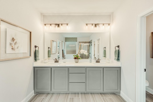 full bathroom with baseboards, a sink, toilet, and double vanity