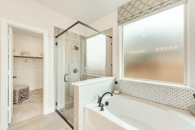 full bathroom featuring a garden tub, a shower stall, and a walk in closet