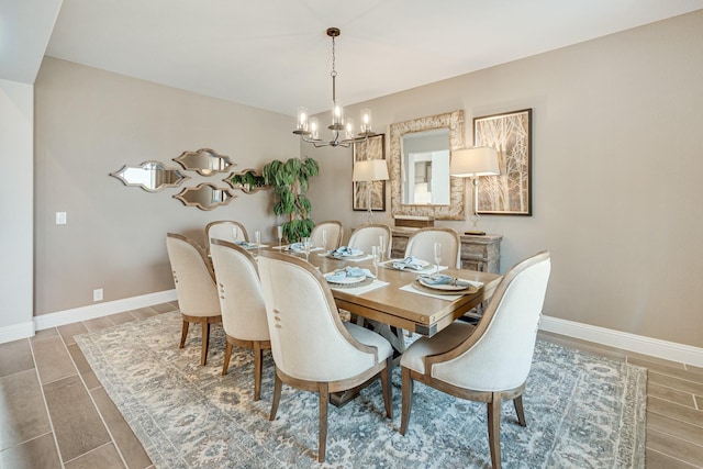 dining area featuring wood tiled floor, baseboards, and an inviting chandelier