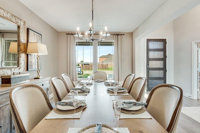 dining room with wood finished floors, visible vents, baseboards, and an inviting chandelier