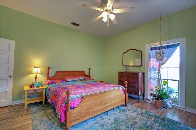 bedroom featuring ceiling fan, wood finished floors, visible vents, and baseboards