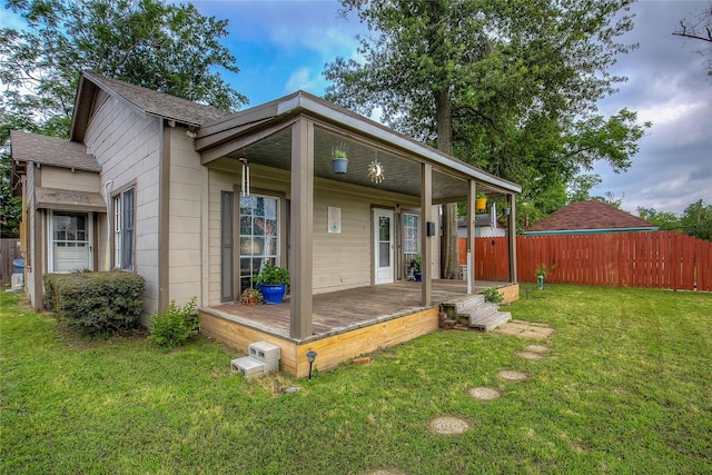 back of house featuring a shingled roof, a lawn, and fence