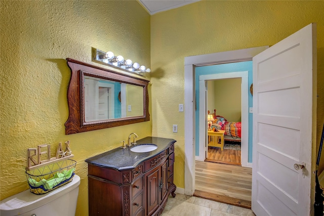 bathroom featuring a textured wall, toilet, connected bathroom, vanity, and tile patterned flooring