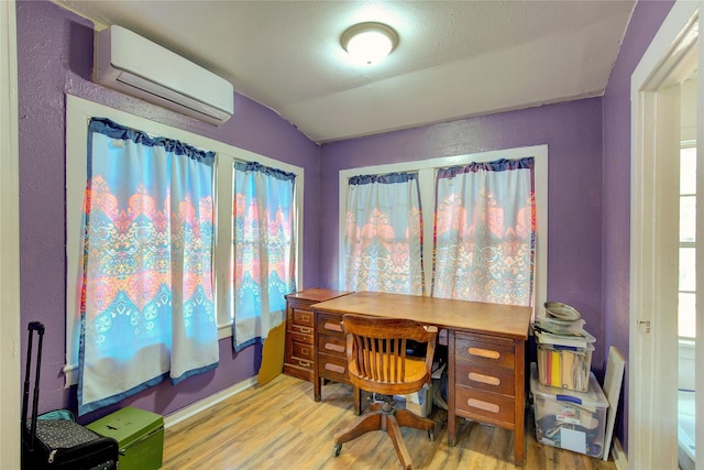 office area with vaulted ceiling, a wall mounted air conditioner, and light wood-style floors