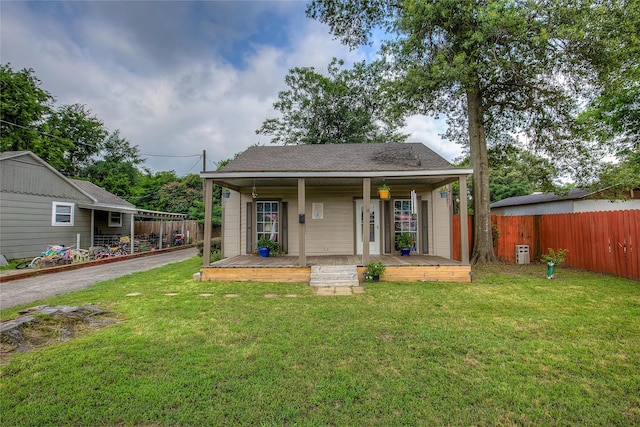 view of front of home with a shingled roof, fence, and a front yard