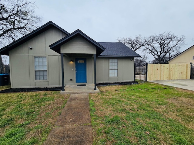 bungalow with a front lawn, a shingled roof, fence, and a gate