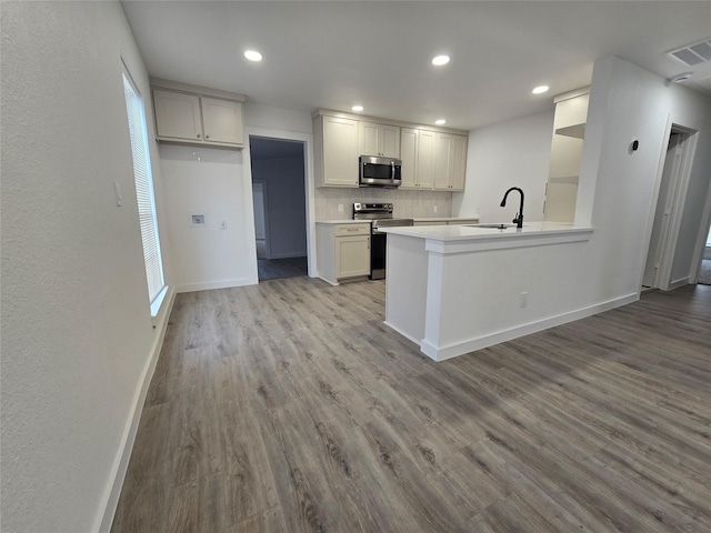 kitchen featuring stainless steel appliances, tasteful backsplash, visible vents, a sink, and wood finished floors