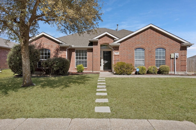 single story home with brick siding, a front yard, and a shingled roof