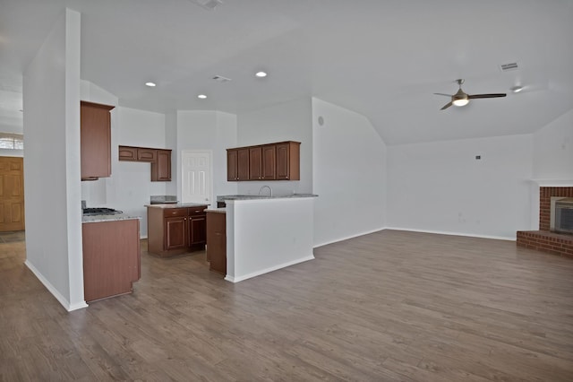 kitchen featuring a fireplace, wood finished floors, visible vents, open floor plan, and vaulted ceiling