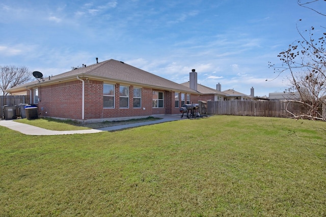 back of property featuring central air condition unit, brick siding, fence, a lawn, and a patio area