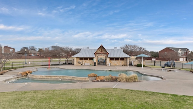 community pool featuring an outbuilding, a patio, fence, a lawn, and an exterior structure