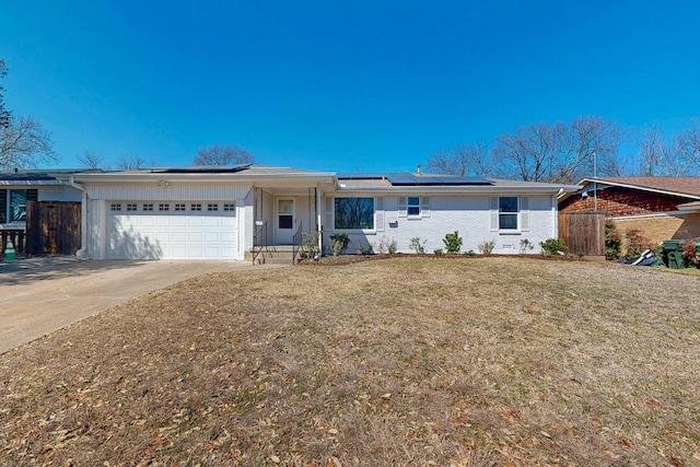 ranch-style house with a garage, solar panels, fence, concrete driveway, and a front yard