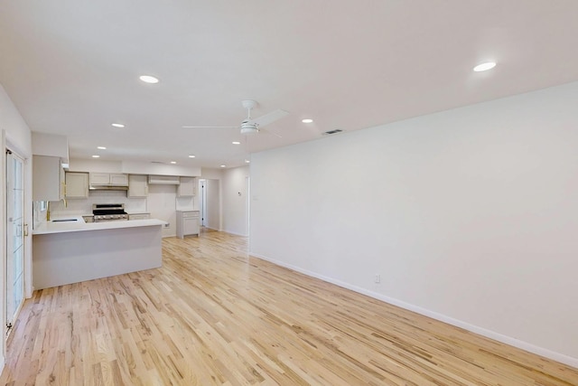 kitchen with gray cabinetry, a peninsula, a sink, electric stove, and light wood-type flooring