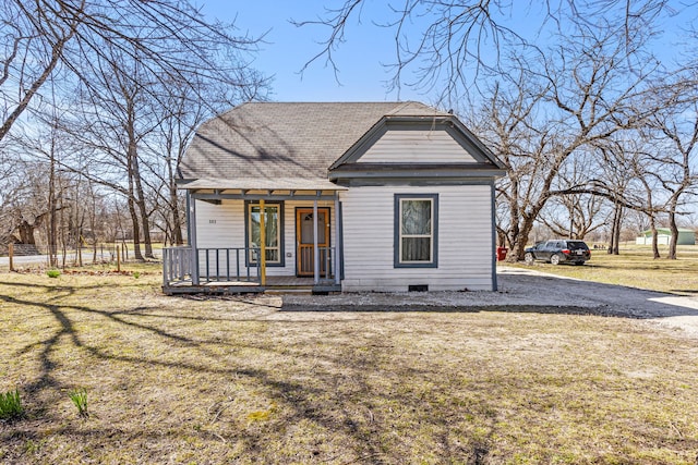 view of front facade with roof with shingles, a porch, crawl space, and a front yard