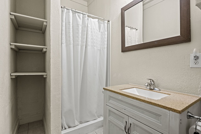 bathroom with a stall shower, tile patterned flooring, a textured wall, and vanity