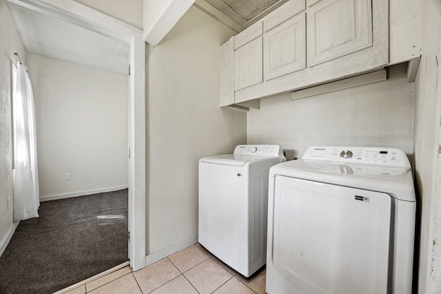 clothes washing area featuring washing machine and clothes dryer, light tile patterned floors, cabinet space, light carpet, and baseboards