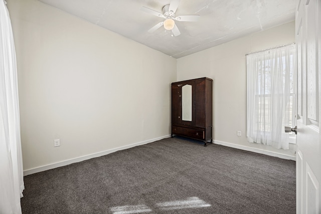 unfurnished room with dark colored carpet, ceiling fan, and baseboards