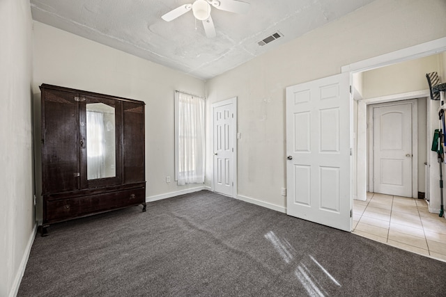 unfurnished bedroom with visible vents, baseboards, ceiling fan, carpet, and tile patterned flooring