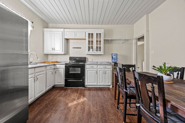 kitchen featuring dark wood-style floors, white cabinetry, a sink, stainless steel fridge, and black / electric stove