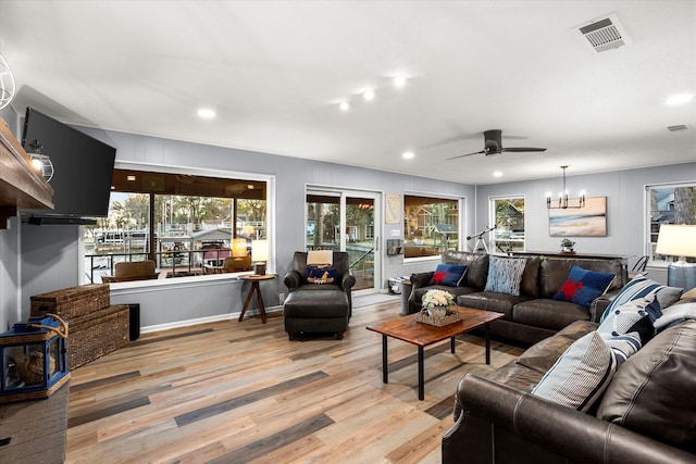 living room featuring ceiling fan with notable chandelier, light wood-type flooring, visible vents, and recessed lighting