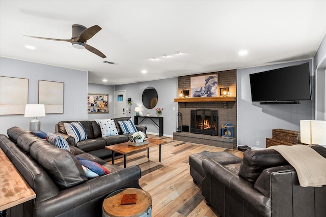 living area with baseboards, light wood-style flooring, ceiling fan, a brick fireplace, and recessed lighting