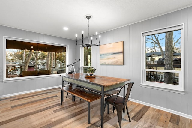 dining area featuring a wealth of natural light, a notable chandelier, baseboards, and wood finished floors