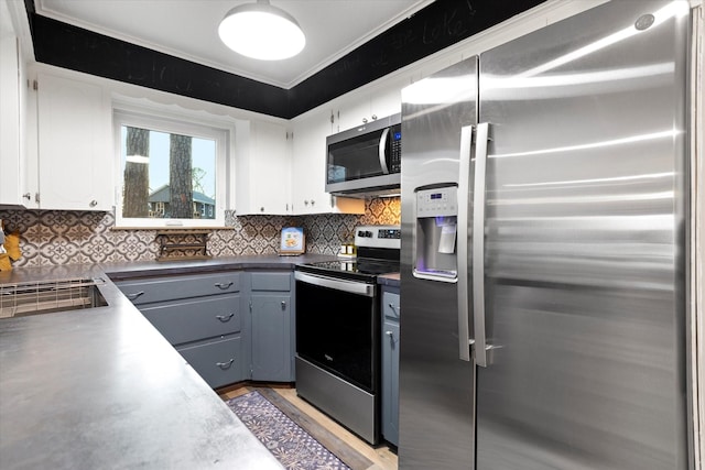 kitchen featuring stainless steel appliances, dark countertops, tasteful backsplash, light wood-style floors, and white cabinets