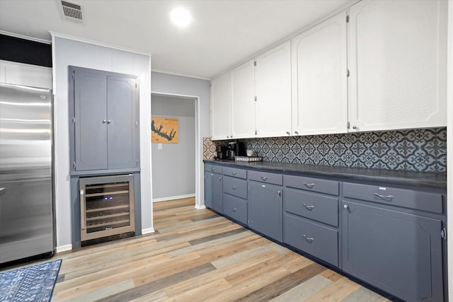 kitchen featuring wine cooler, tasteful backsplash, dark countertops, white cabinets, and stainless steel built in refrigerator