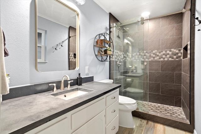 bathroom with a stall shower, vanity, toilet, and wood finished floors