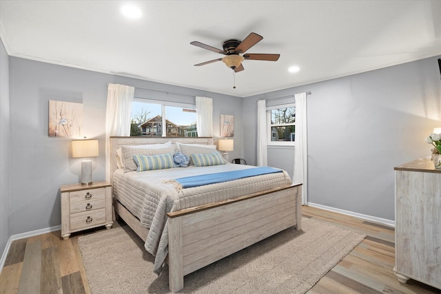 bedroom with light wood-type flooring, multiple windows, and baseboards