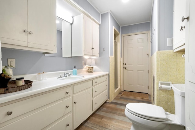 kitchen featuring tile walls, light countertops, light wood-style floors, white cabinetry, and a sink