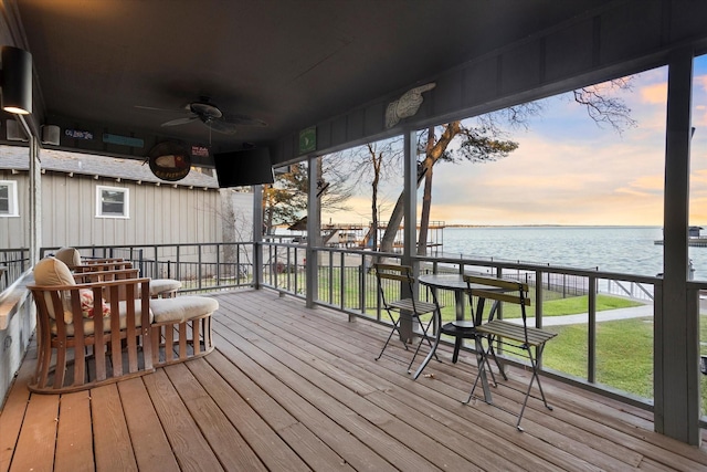 deck at dusk featuring ceiling fan and a water view