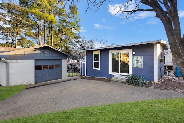 view of front facade featuring a garage, driveway, fence, an outdoor structure, and brick siding