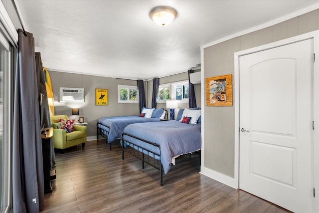 bedroom with dark wood-style floors, baseboards, and a wall mounted AC